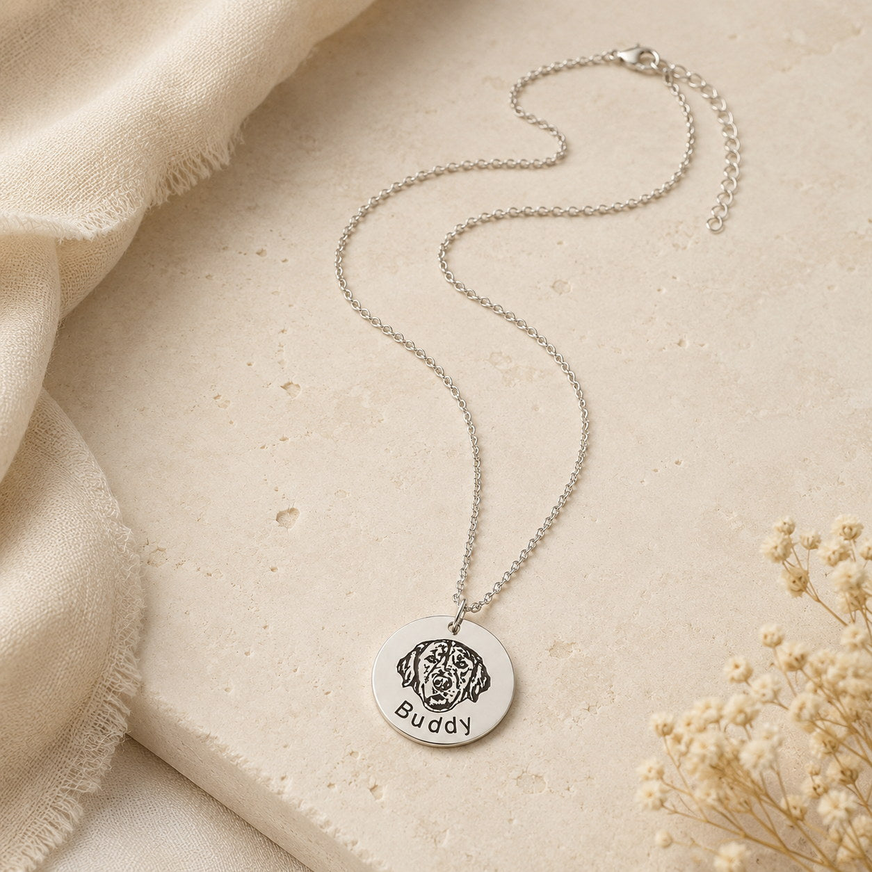 Silver Round Portrait Engraved Necklace styled on fabric with small flowers