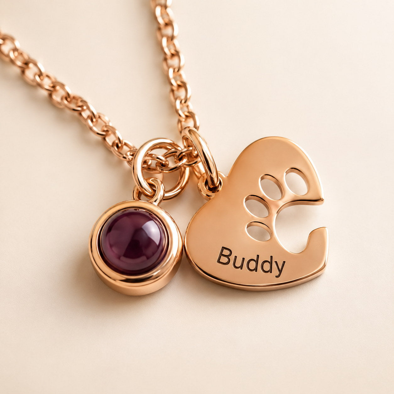 Rose gold Paw Heart Birthstone Necklace close-up with red birthstone and Buddy engraving